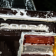 a close-up photo of the 2002tii badge on the back of the burgundy BMW. the car is in the middle of a deep clean, and the bodywork is covered in sudsy water running off the car.